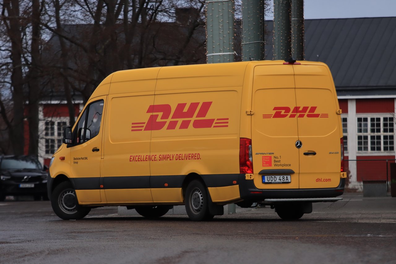 services-01 Yellow DHL van on street showing company branding and delivery services.