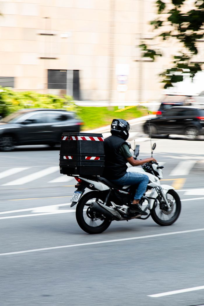 about-01 Motorcyclist delivers packages swiftly through busy city streets.