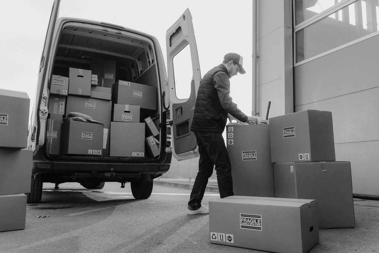 why-choose-us Delivery driver unloads packages from a van, organizing shipments outdoors.